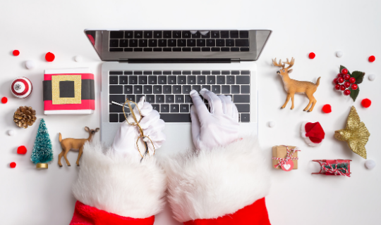 Santa typing on laptop with Christmas decorations