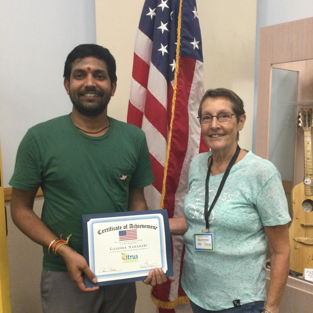 Adult Literacy Student Ganesha holding a certificate of achievement for passing the Naturalization exam with his Tutor Pam