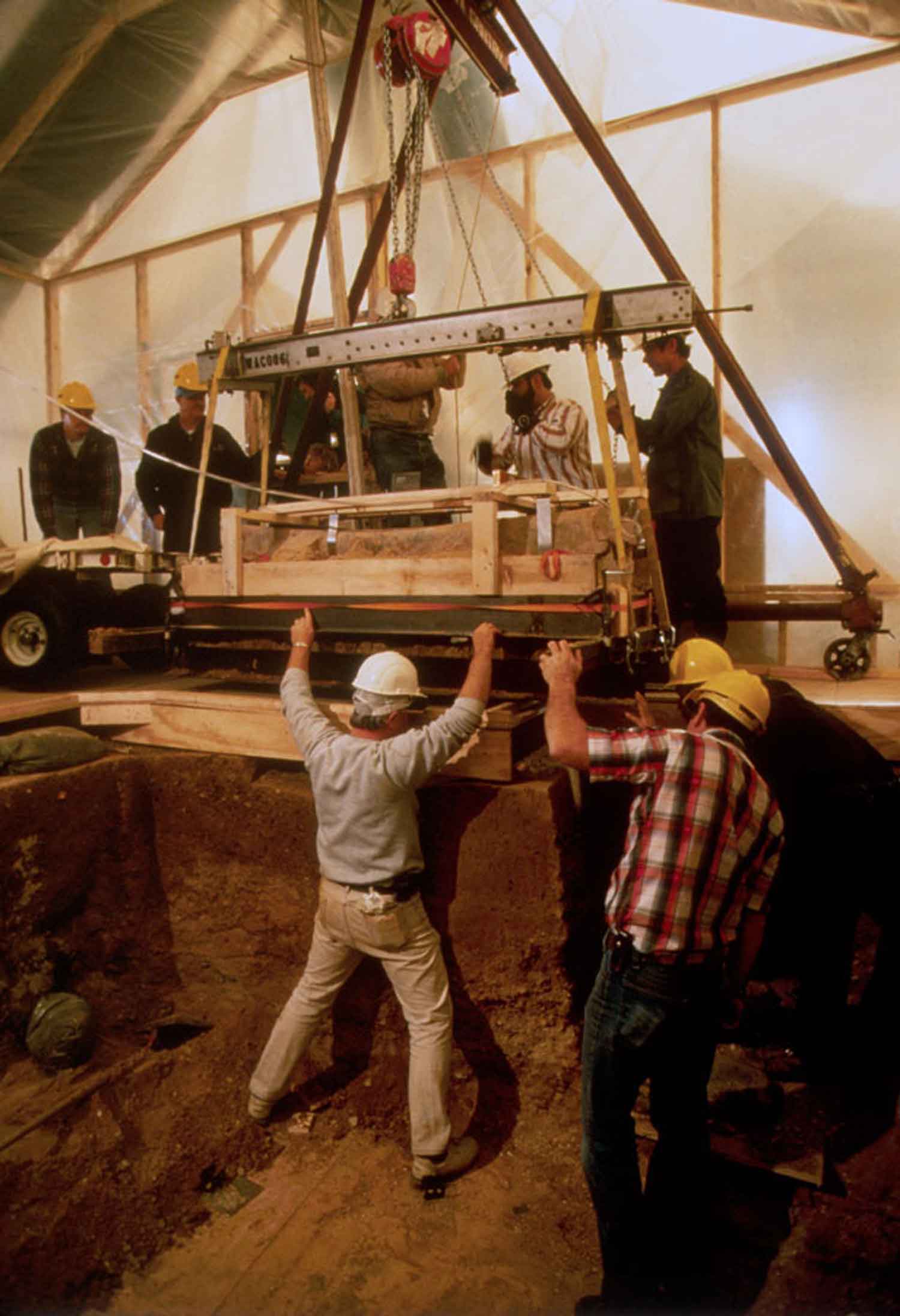 Team of Archaeologists lifting one of the lead coffins from dig sit with a crane